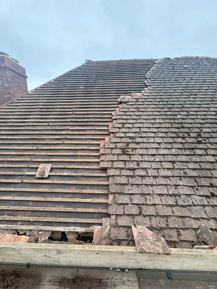 Roof half stripped showing old tiles and new battens